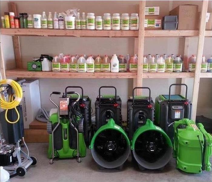 A wooden shelf filled with SERVPRO brand cleaning supplies.