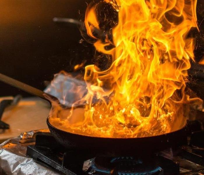 A frying pan on fire sitting on a stovetop.