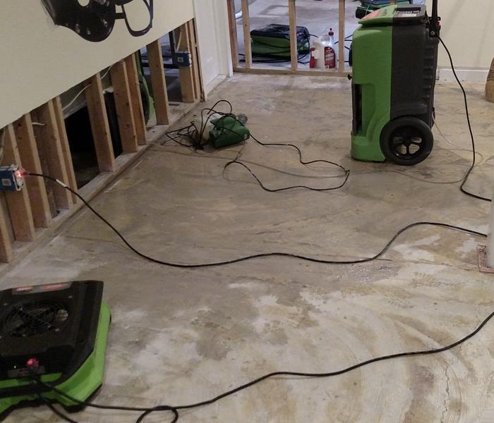 A water stained basement floor with SERVPRO drying equipment.